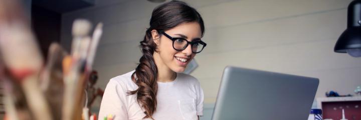 woman sits in front of laptop happily working in office room