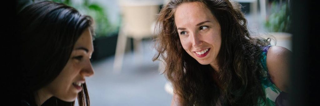 two women happily talk discuss in coffee shop