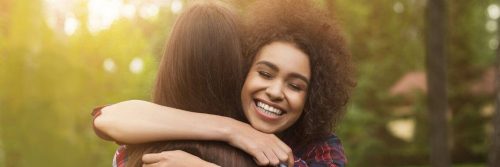 curly hair woman hugging college smiling happily in sunny sky
