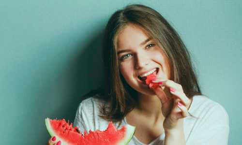 A woman eating a wedge of watermelon
