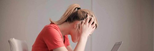 woman scratching head looking at laptop sitting in quiet room