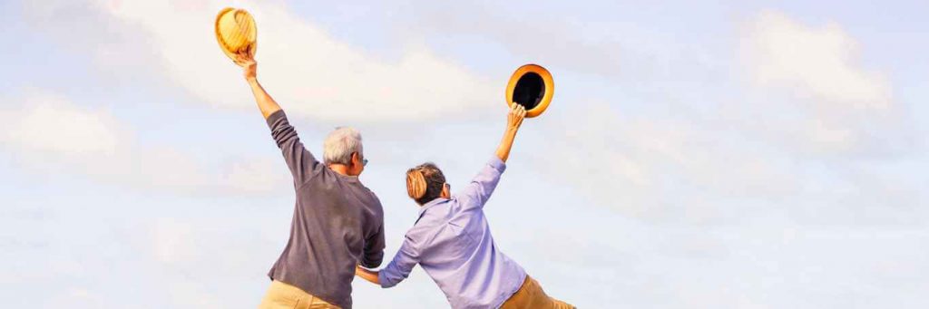 couple hand in hand stands backward raises hands holding yellow hat