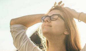 woman stands hand on hair eyes closed gratitude life
