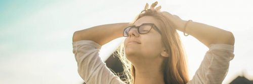 woman stands hand on hair eyes closed gratitude life