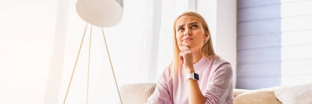 woman sits on couch beside lamp thinking making decision