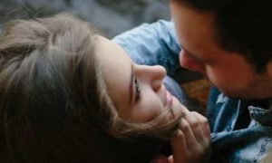 couple stands on bridge looking hugging each other