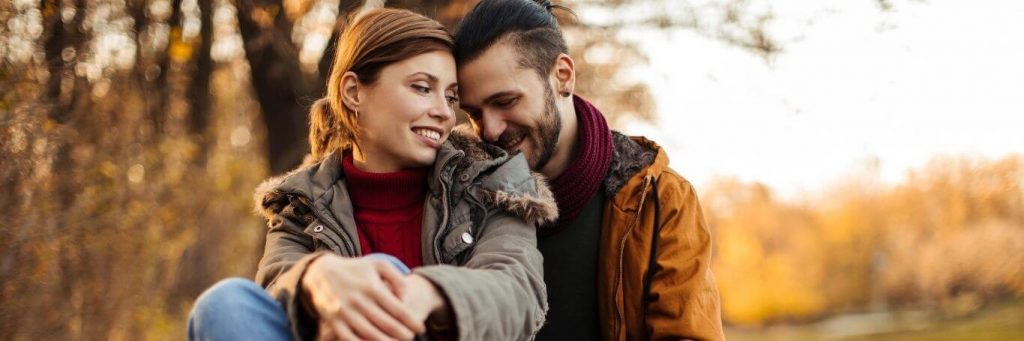 couple happy faces sit in park smiling