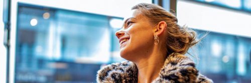 woman happily smiles looks through window