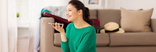 woman sitting beside couch talking on phone in living room