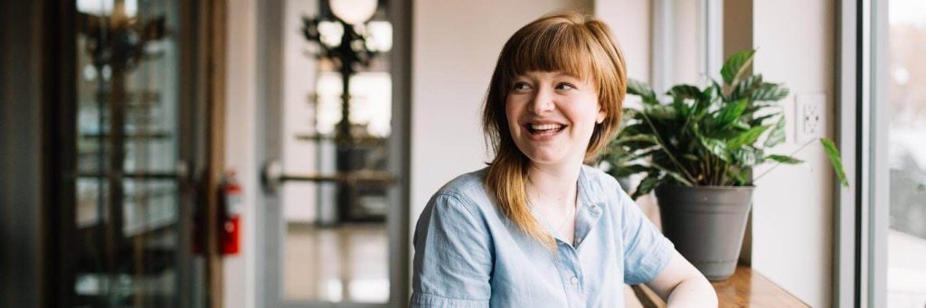woman sits alone in coffee shop smiling