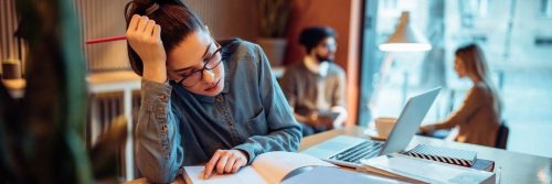 woman sits in coffee tiredly stressed studying