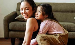 woman carries adorable daughter smiles sitting beside couch in living room