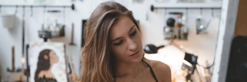 woman sits in painting room focuses on drawing