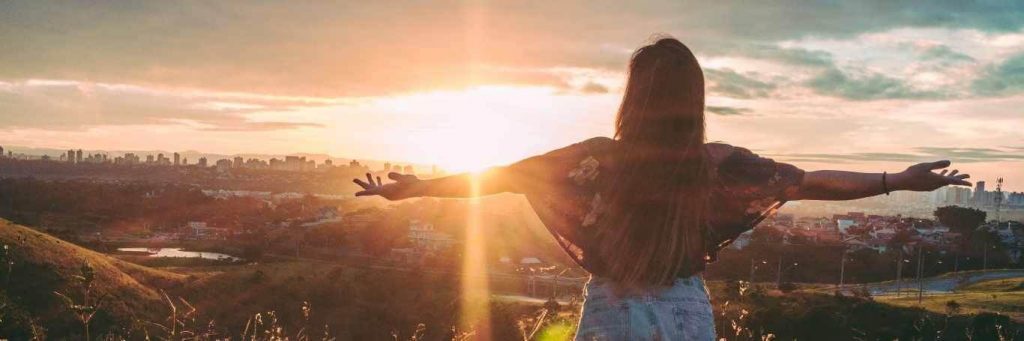woman stands facing backward gratitude life in beautiful sunny sky