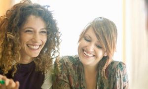 two women sits happily respectfully talking smiling at man
