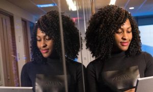 curly black hair woman stands in office working looking at tablet