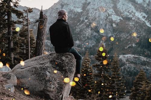 A man sitting on a rock looking at a mountain