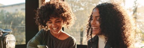 two curly hair women sits talking laughing