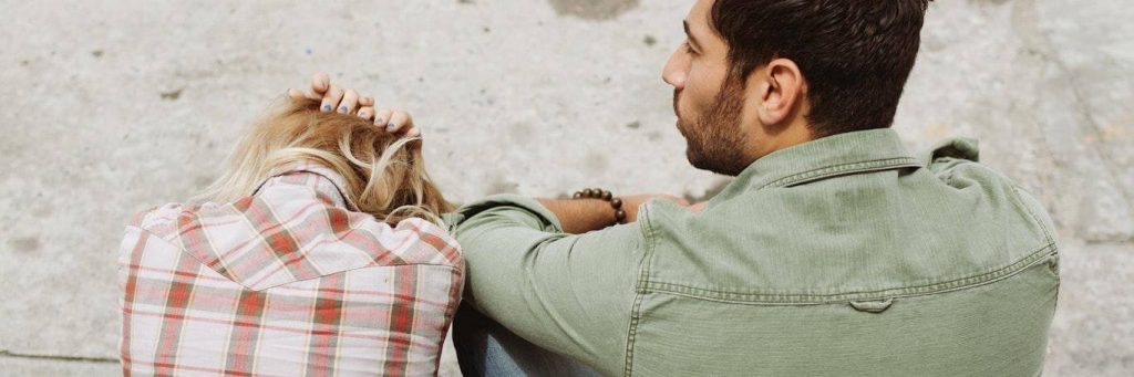 woman sits beside man scratching hair crying feeling depressed