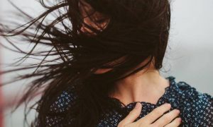 woman hand on chest hair flying covering face