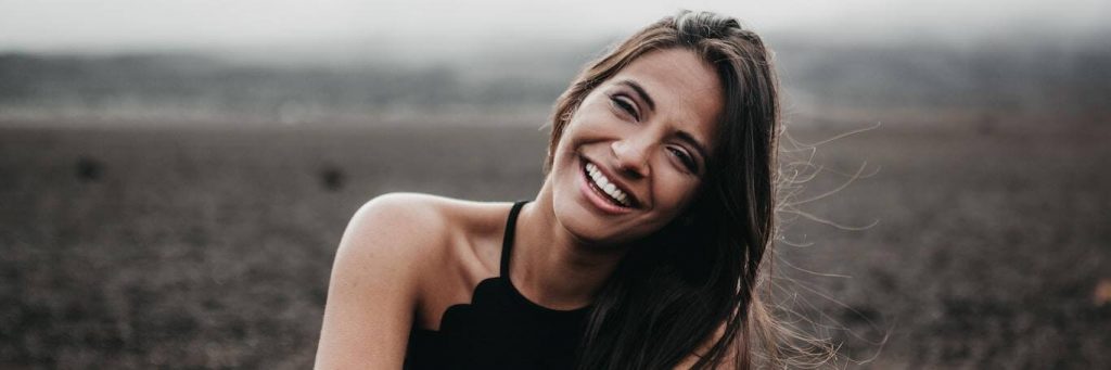 woman stands on field happily smiles