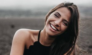 woman stands on field happily smiles