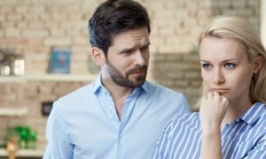 girl pissed off hand on chin while partner standing beside looking at her in kitchen