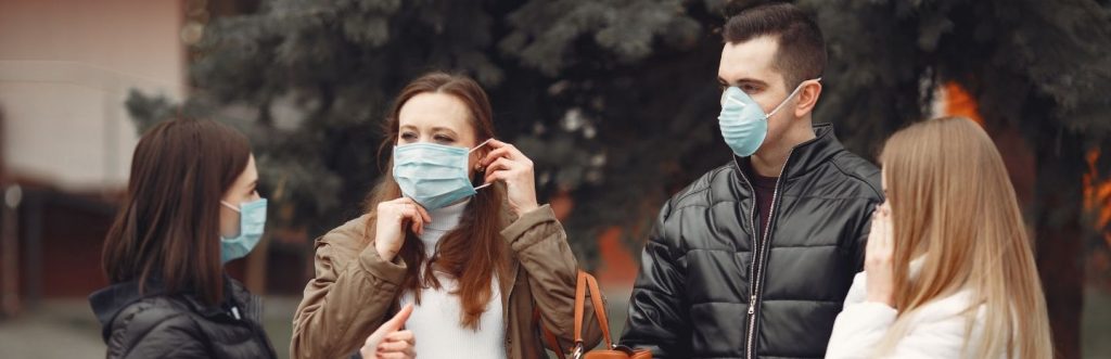 group of mixed genders wearing face masks standing on street talking