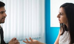 man wearing black vest asks for help while woman consulting him