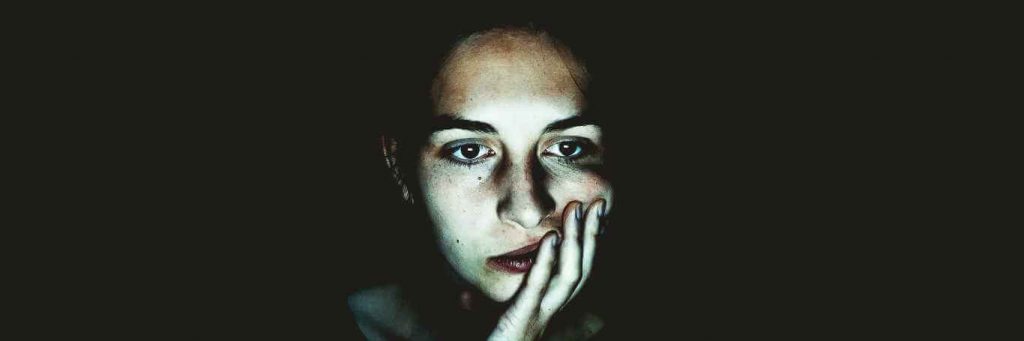 woman sad depressing face hand in face upset in dark