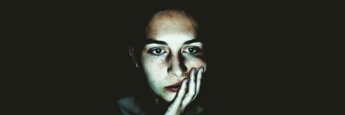 woman sad depressing face hand in face upset in dark
