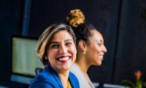 two women sit in office smiling at man sitting beside
