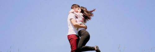 couple stands hugging each other in blue sky