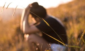 man sadly sits on field thinking