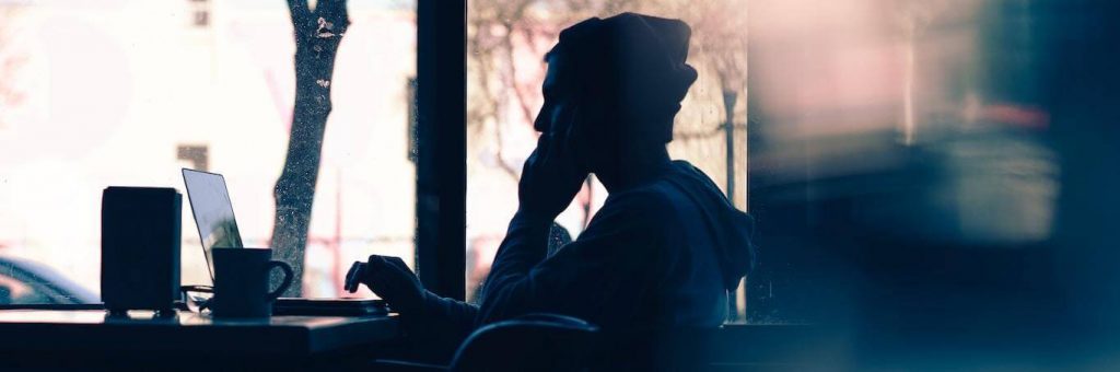 man sits alone in office focuses on work beside mug