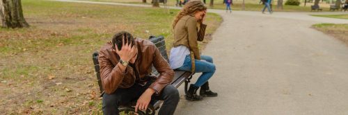 couple sits on bench in park head on face having conflict not talking to each other