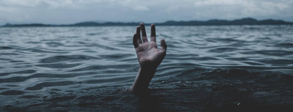 hand raises over water ocean in overcast weather
