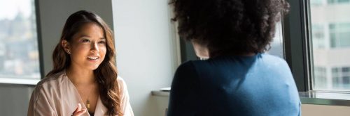 two women sits in office talking