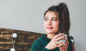 woman smiles holds white mug