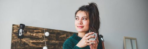 woman smiles holds white mug