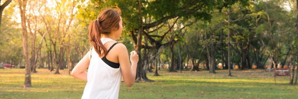 woman exercises jogs in park in sunny sky