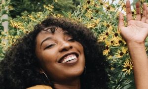 curly hair woman lies on sunflower garden happily smiling immersing into nature