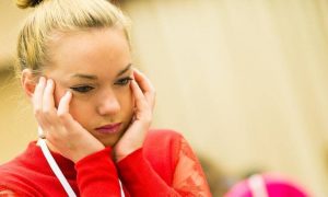 woman sits hand in face feeling stressed