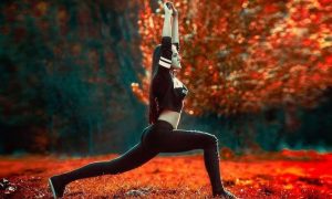 young woman stands in red leaves forest stretching practicing yoga