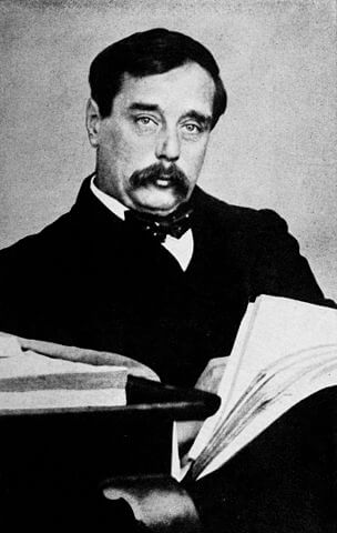 Science-fictiion author H.G. Wells sites with a book in his arms.