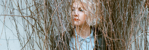 woman sadly stands between trees