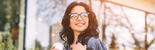 long curly black hair lady happily smiles hand holding white cup
