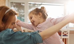 young lady plays with little adorable daughter in living room