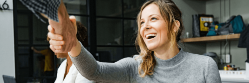 woman sits in office smiling shaking hand